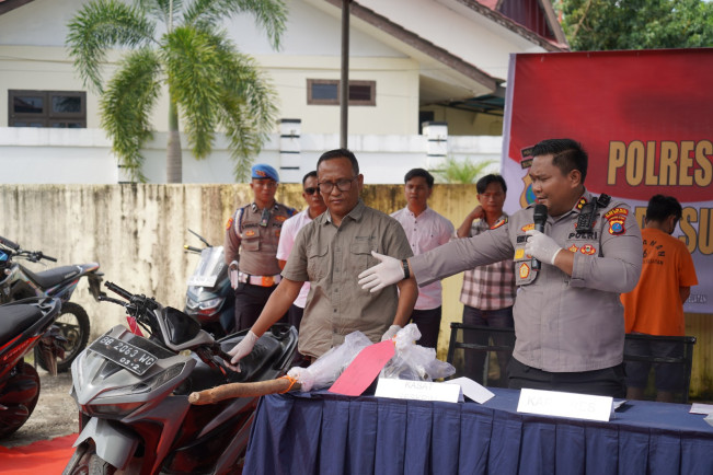 Polisi menunjukkan barang bukti cangkul. [Istimewa]